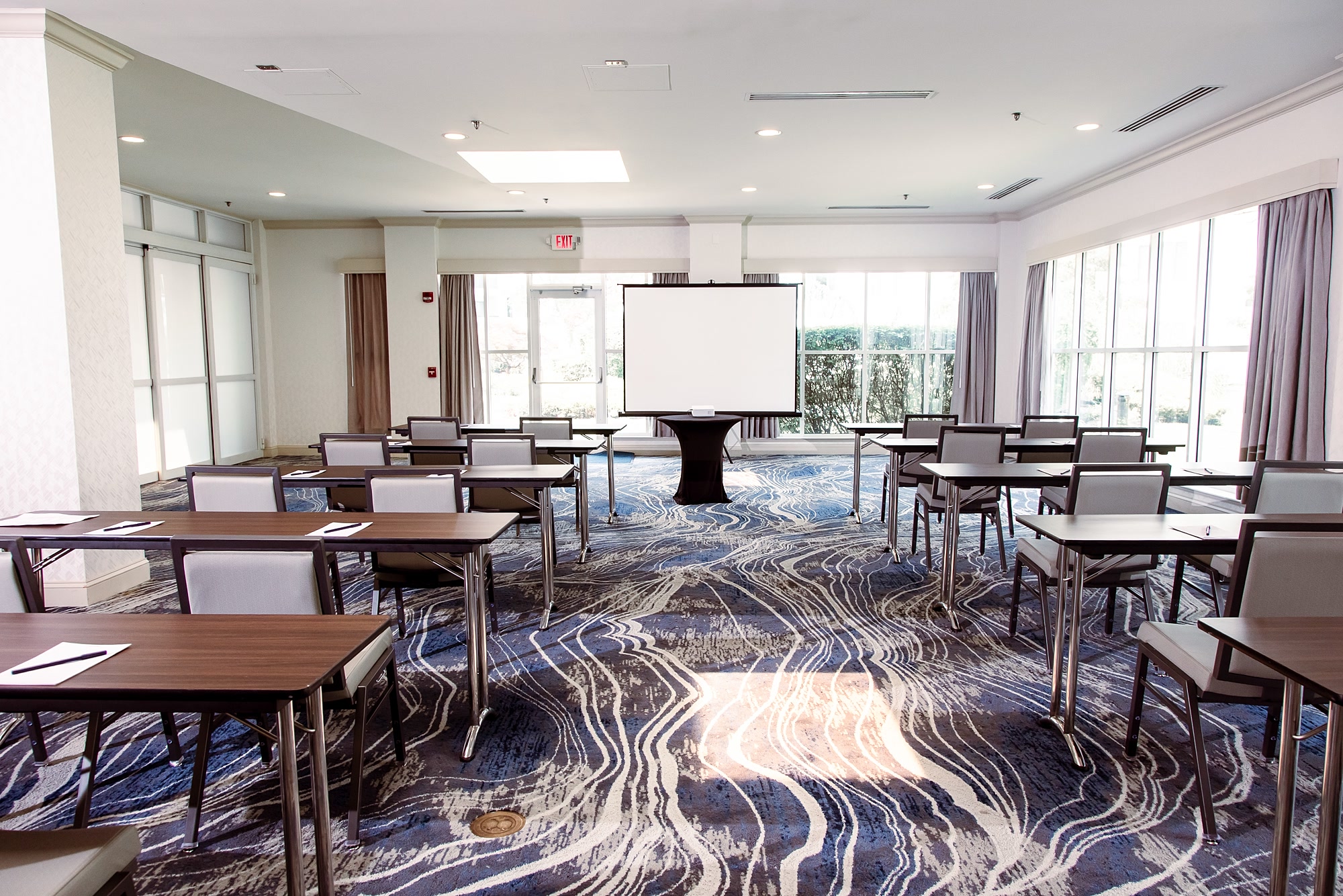 Breakout room set classroom style with a projection screen beside a daylight window wall