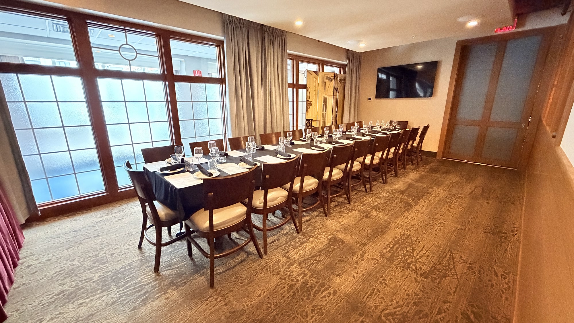 One long table set for a private dinner at Redz beside a wall of windows